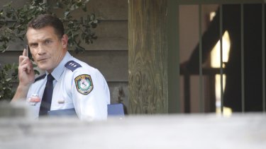 A police officer outside Craig Thomson's home.