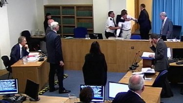 The protester is restrained by security as Tony Blair, left, was speaking at the Leveson Inquiry.