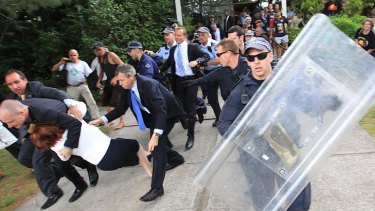 Julia Gillard is dragged to a car by her security team amid clashes between police and protesters.