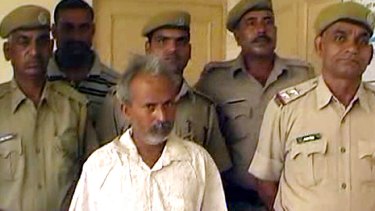 A screenshot shows Indian marble miner Oghad Singh (centre) in police custody after turning himself in following the brutal attack on his daughter.