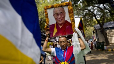 A Tibetan exile carries a portrait of Tibetan spiritual leader, the Dalai Lama, at a rally in New Delhi, India.