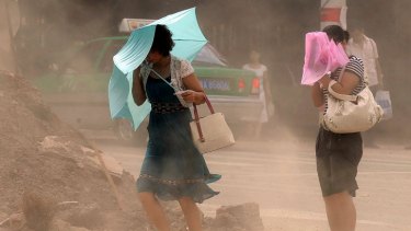 Two Chinese women struggle as they make their way along a polluted street in Hefei, eastern China's Anhui province.