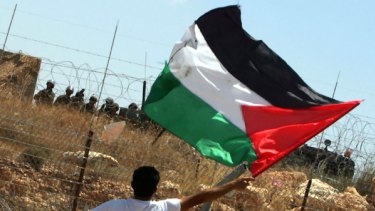 A Palestinian demonstrator waves his national flag opposite Israeli soldiers. Australia's unquestioning support for Israel ignores the plight of the Palestinians.