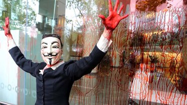 A protester smears fake blood on the immigration office in Lonsdale Street while a crowd chants that the government has blood on its hands over this week's violence on Manus Island.