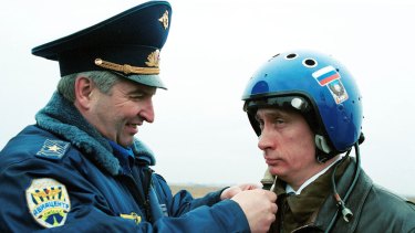Russian air force general Alexander Kharchevsky adjusts a helmet on Vladimir Putin, then Russia's acting president, before he flew into Chechnya in a fighter jet on March 20, 2000. 