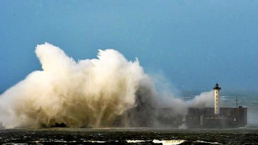 Large waves break against the dyke at the entrance of the port of Boulogne, northern France.