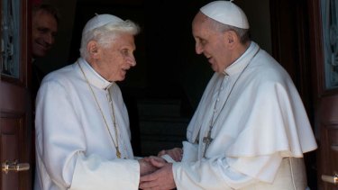 Double take: Pope Francis, right, greets his predecessor, Pope Emeritus Benedict XVI, on his arival back at the Vatican.
