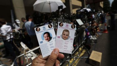 Cards depicting the 'royal baby', either as a boy or a girl, specially made by a games company as a publicity stunt are pictured, backdropped by members of the media waiting across the St. Mary's Hospital exclusive Lindo Wing in London.