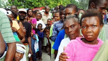 People wait in line to receive water in Port-au-Prince.