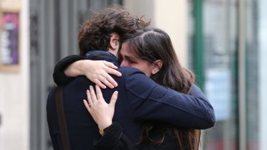 A couple embrace after laying flowers at the La Belle Equipe cafe in Paris on Saturday.