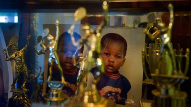 Photographs taken when Franklin and Francis Tiafoe were toddlers sit at the back of a cabinet filled with trophies in their apartment.