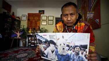 Htoo Htoo Han, a Burmese refugee, holds up a 1988 photo which he say shows him (right) posing as a student leader while working as a lieutenant in Burma's military intelligence.