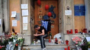 Tears ...  a candle is lit in front of the bank in Athens where three people died.