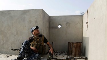 An Iraqi federal police soldier seeks cover on a roof of a house in Mosul.