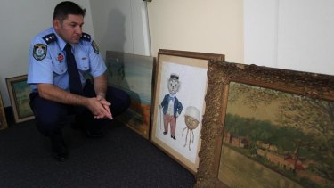 Inspector Ian Woodward looks at the art found at a Sydney house.