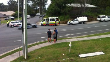 The father of the man (left) at the centre of a siege on the Gold Coast talks with his son's partner and police officers at the end of the street which has been shut down for the past 17 hours.