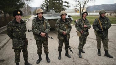  Ukrainian soldiers and a Ukrainian army tank stand just inside the gate at a Ukrainian military base that was surrounded by several hundred Russian-speaking soldiers in Crimea.