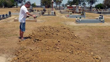 A man pours beer on the mounds of dirt where Ned Kelly was buried on Sunday at the Greta cemetery.
