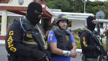Last of a long line &#8230; Daniel Barrera is escorted by members of Venezuela's National Guard after he was arrested while using a tapped public phone.