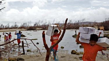 Locals carry aid packages after Cyclone Haiyan.