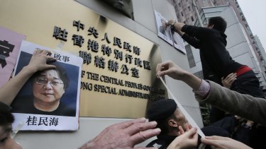 Protesters in early January try to display photos of the missing booksellers outside the Liaison of the Central People's Government in Hong Kong in 2016. 