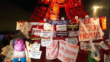 A participant puts posters on the mini red Eiffel Tower as NGO representatives staged a sit-in protest in Paris.
