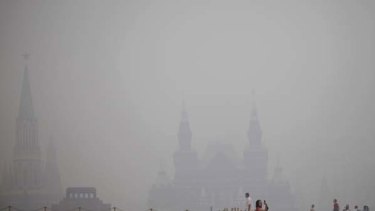 A tourist takes pictures at Red Square in a thick blanket of smog.
