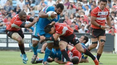 Italy's Manoa Vosawai is tackled by Japan's fullback Ayumu Goromaru and captain Michael Lieitch in Tokyo.
