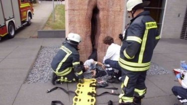 Rescuers works to free the young man trapped in a sculpture of a vulva at Tubingen, Germany.