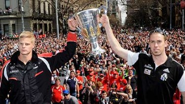 Opposing skippers Nick Riewoldt, left, and Nick Maxwell hoist the cup at the top of Collins Street after today's parade.