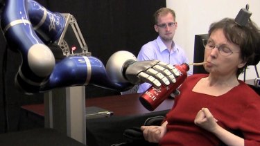 Cathy Hutchinson sips a drink held by a robotic arm.