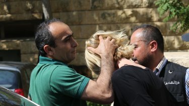 A Lebanese plainclothes policeman prevents Tara Brown from looking towards journalists as she was taken from the courthouse while under arrest in Lebanon.