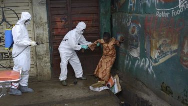 A woman suspected of being infected with Ebola is assisted by health workers to an ambulance for treatment in Freetown, Sierra Leone.