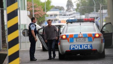 Police custody ... Phil Rudd, 60, dressed in jeans and a grey sweater.