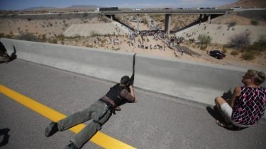 Eric Parker from central Idaho aims his weapon from a bridge as protesters gather by the Bureau of Land Management's base camp.