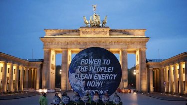 Members of Greenpeace pose with a giant placard in front of the Brandenburg Gate in Berlin on Sunday.