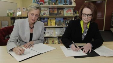 Prime Minister Julia Gillard signs the Gonski school funding agreement with ACT Chief Minister Katy Gallagher at Lyneham High School in Canberra on Thursday.