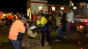 Residents, emergency crews and members of the army rush to sandbag Weir Street