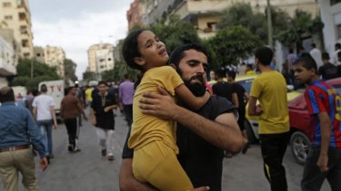 A Palestinian man carries away a girl, that was overcome by emotion, during the funeral of 7-year-old Muhammed Abu Shagfa.