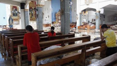 Residents pray inside a damaged Catholic Church after super Typhoon Haiyan battered Tacloban city.