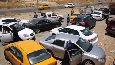 Iraqis - predominantly from Tikrit - parked by the side of the highway after crossing a checkpoint south of Kirkuk into the Kurdish Peshmerga-controlled zone after fleeing Iraqi areas overrun by jihadists from ISIL.