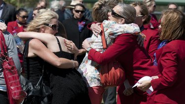 Family and friends comfort each other at a moving memorial service.