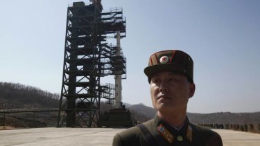 A soldier stands guard in front of a rocket in North Korea.