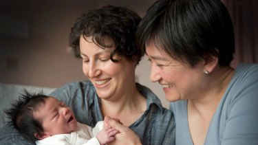 Early arrival: Senator Penny Wong holds hands with new daughter Alexandra in Adelaide as partner Sophie Allouache looks on.
