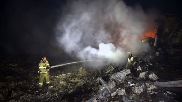 A firefighter douses flames from the wreckage of the Malaysia Airlines plane.