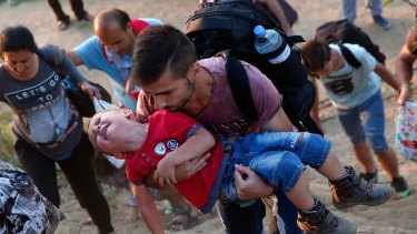 A young Syrian boy cries as his father carries him up a steep hill as they walk to a crossing on the Greek border with Macedonia.