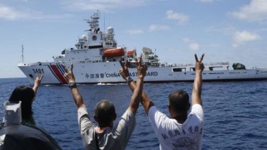 Philippines Marines and a television reporter on board a supply ship gesture towards a Chinese coastguard vessel near Second Thomas Shoal in the South China Sea on March 29.