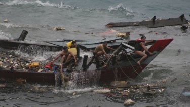 Asylum seekers cling to the wreckage of their boat as it takes water near Flying Fish Cove on Christmas Island last December.