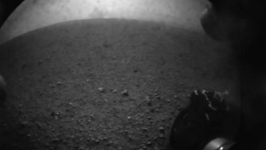 In this image from NASA TV, shot off a video screen, one of the first images from the Curiosity rover is pictured of its wheel after it successfully landed on Mars.