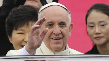 Pope Francis waves upon his arrival at Seoul Air Base as South Korean President Park Geun-hye (left) looks on.